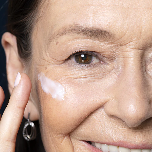 Mujer de edad madura aplicándose crema hidratante
