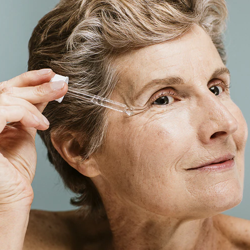 Mujer mayor aplicando serum antiedad y antiarrugas en su rostro