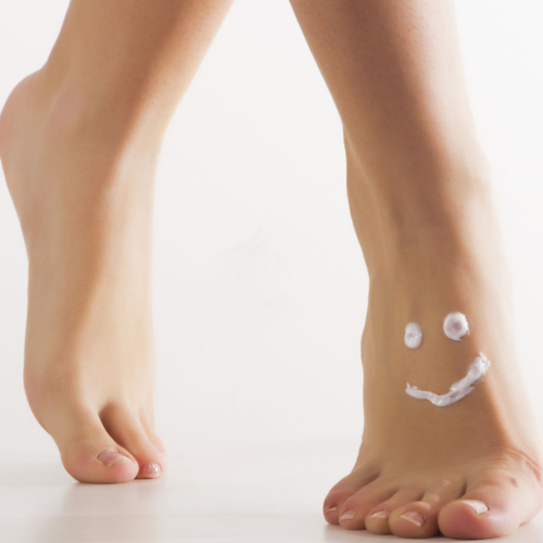 Pies de mujer con loción hidratante en forma de una cara feliz