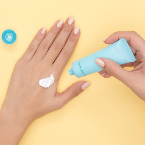 Aplicación de crema hidratante en la mano de una mujer