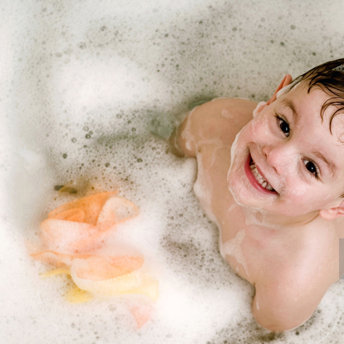 Niño en una bañera con espuma de un shower gel